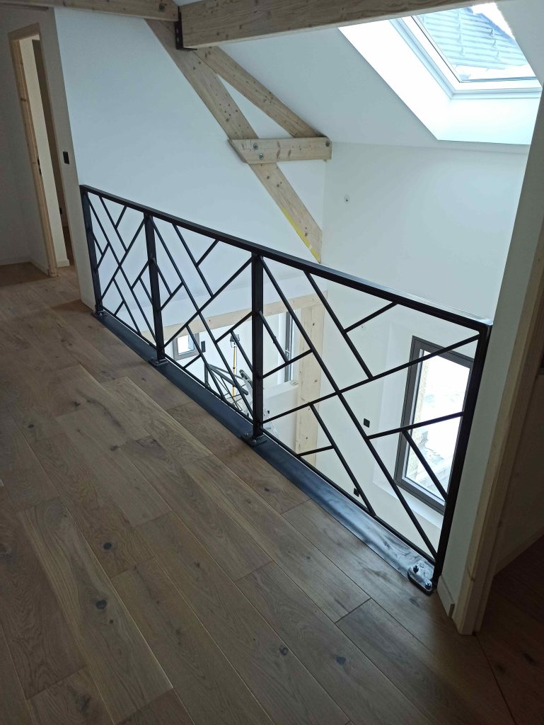 Garde-corps de mezzanine en acier brut, le long du parquet sous la charpente en bois.