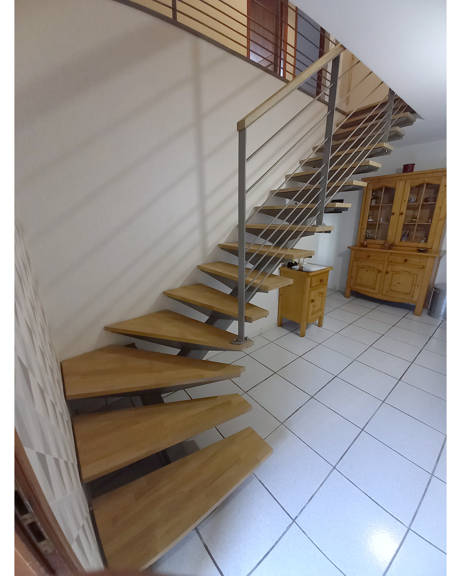 Vue d’ensemble de l’escalier en acier gris et chêne, avec départ quart tournant et rampe à lisses.