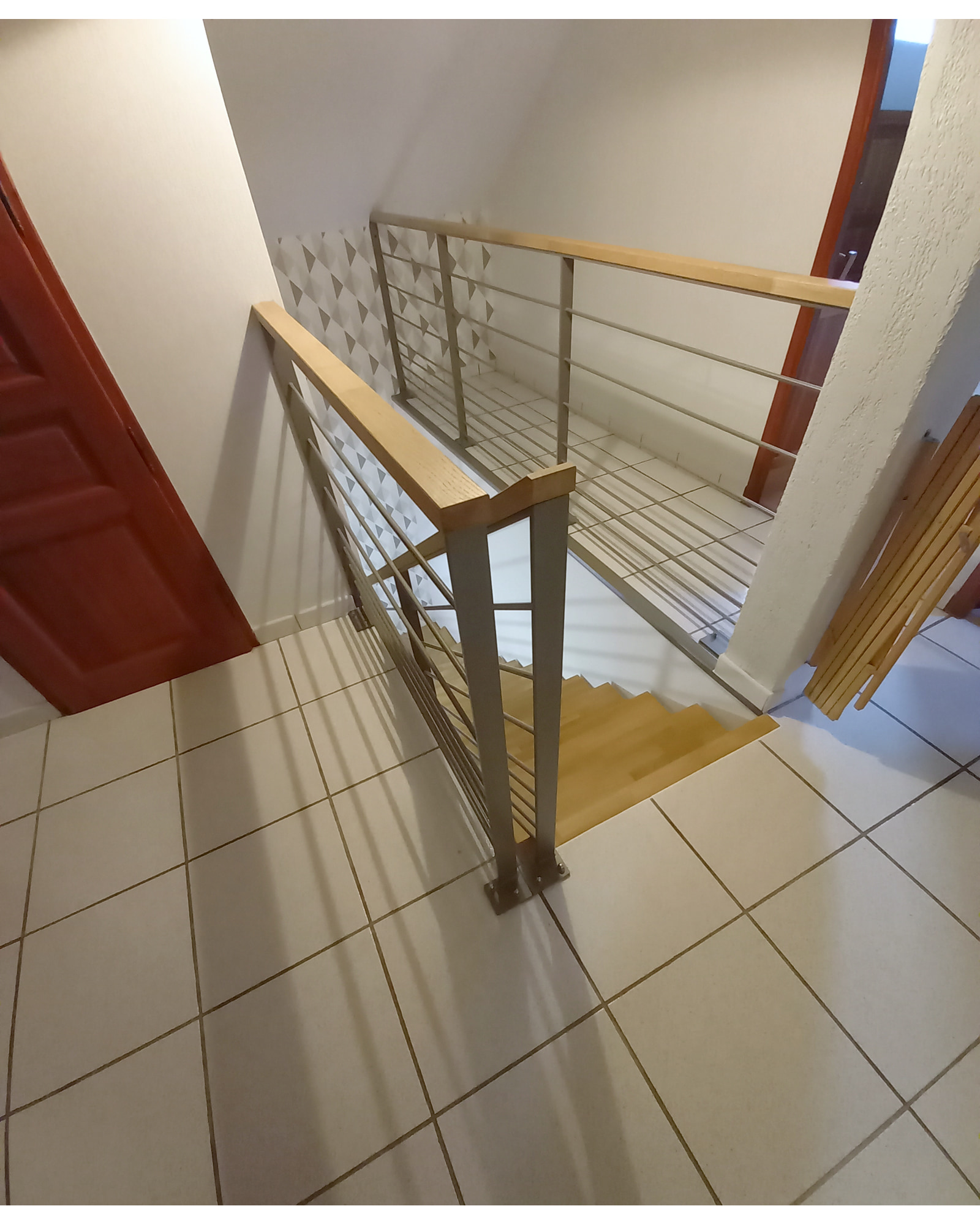 Raccord de la rampe et du garde-corps de palier autour de la trémie, avec mains courantes en bois.